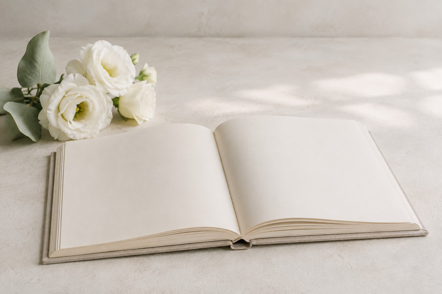 An open memory book beside white flowers